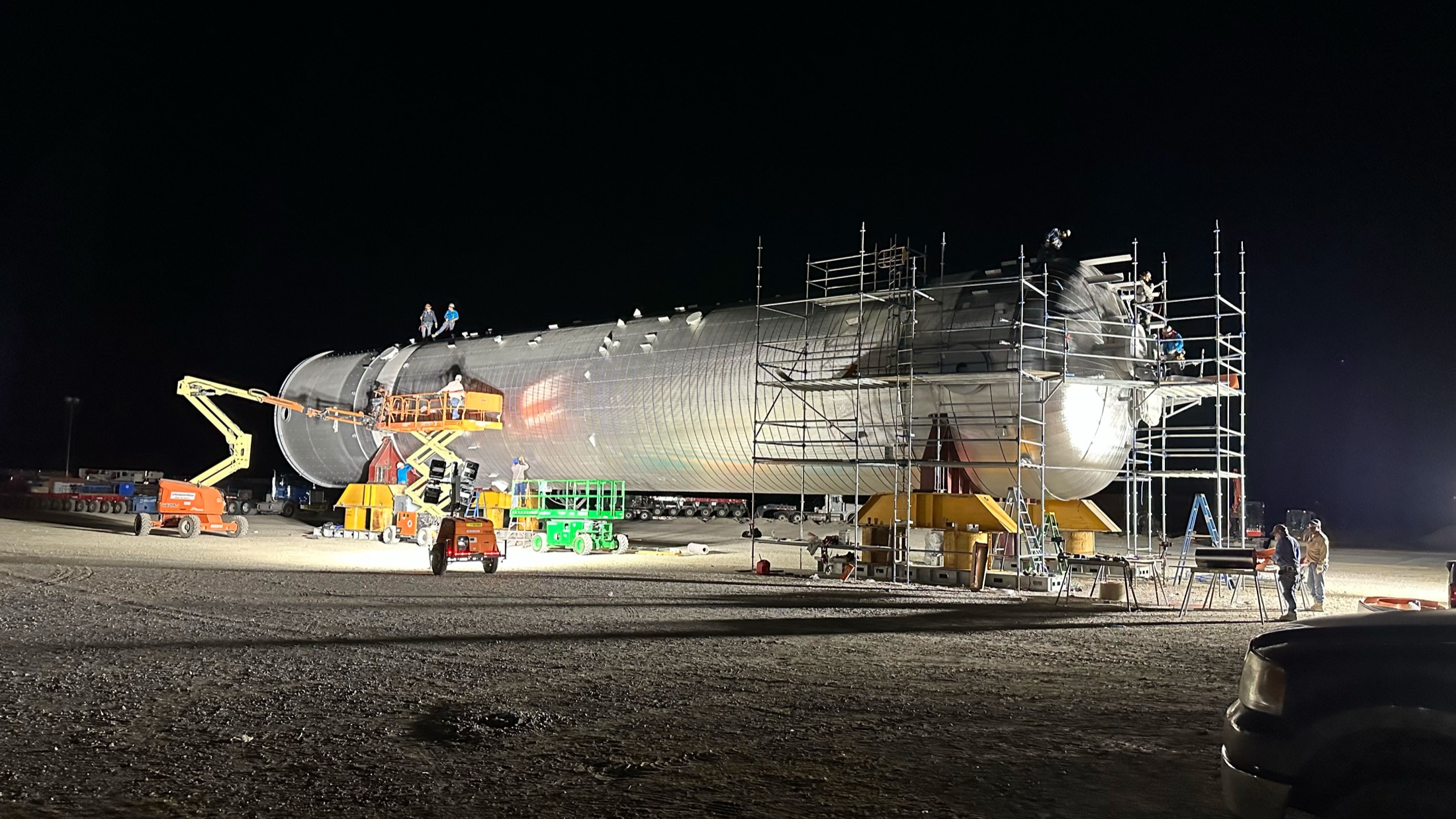 Stellar crews insulating a large process vessel under floodlights during a night shift